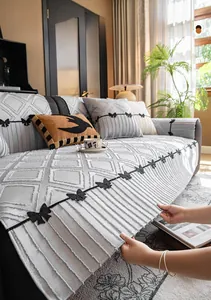 Detail of grey quilted sofa cover with elegant bow tie ribbons and ruffled skirt trim