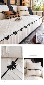 Detail of premium off-white sofa cover with black bow embroidery and thick texture