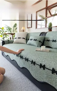 Detail of green chenille sofa cover with woven texture and small black bow accents