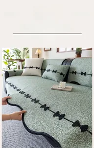 Detail of sage green chenille sofa cover with black bow tie stitching and ruffled edge