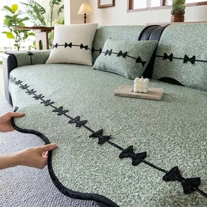 Thick green chenille sofa cover with black bow embroidery and wavy ruffled edges