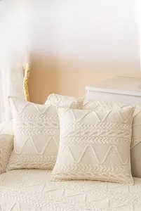Detail des cremefarbenen gesteppten Kissenbezugs mit geometrischer Textur auf Baumwollsofa