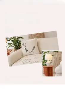 Detailed close-up of cream velvet sofa cushion with minimalist black face line art embroidery