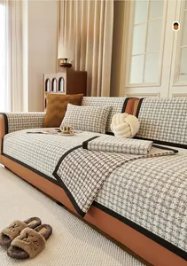 Détail de housse de canapé en chenille pied-de-poule avec passepoil noir et coussin