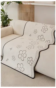Detail of cream chenille sofa mat with brown floral patterns and black contrast piping