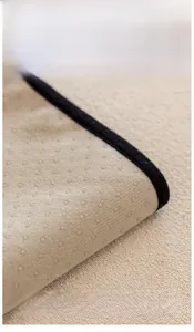 Macro shot of non-slip silicone backing on beige plush sofa cover with anti-skid dots