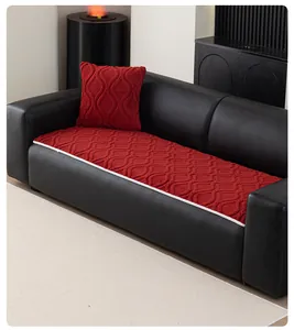 Close-up of red wave-quilted sofa cushion with white braided edges on black leather sofa
