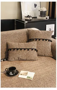 Detailed texture of brown chenille sofa cushion with black pom-pom trim accents