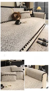 Detail of off-white chenille sofa cover with black pom-pom fringe and matching pillow