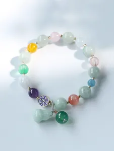 Close-up of multicolor gemstone bracelet with jade gourd pendant and gold spacers