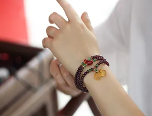 Detail of garnet wrap bracelet featuring green beads and amber chalcedony gourds
