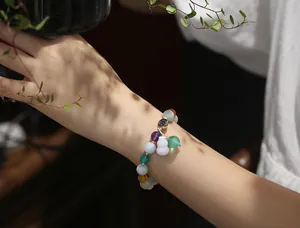 Detail of colorful multi-gemstone beaded bracelet with gourd charm on female wrist