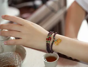Close-up of three-layer garnet beaded bracelet with gourd pendants on a female wrist