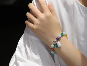 Detailed shot of multi-color gemstone beaded bracelet with purple jade gourd charm on wrist