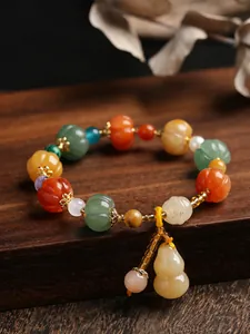 Detailed view of pumpkin-shaped jade beads bracelet with gourd charm and metal bell