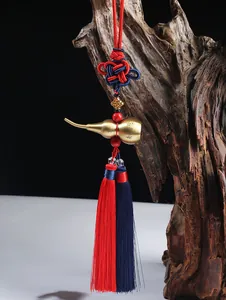 Macro shot of brass gourd car pendant with red and blue Chinese knot on aged wood