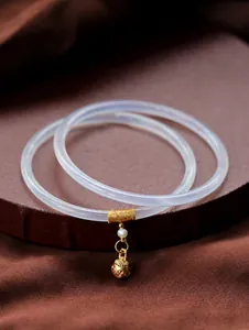 Primer plano de brazalete de calcedonia lavanda con dijes dorados calados y una perla