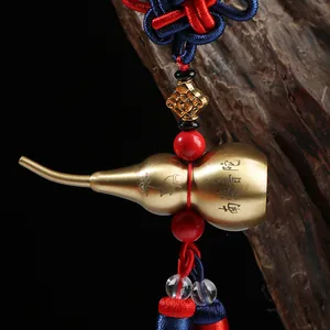 Brass gourd car pendant with Chinese knot and lotus engravings on a dark background