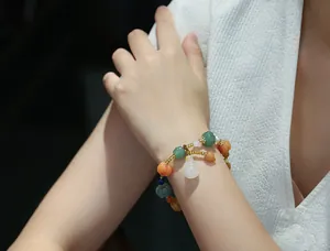 Close-up of gemstone pumpkin bead bracelet with white gourd pendant on woman wrist