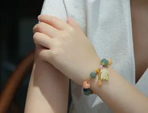 Macro detail of pumpkin and lotus beads bracelet with a yellow leaf jade pendant