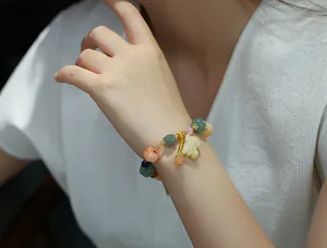 Detailed shot of multicolor carved pumpkin beads bracelet with a leaf charm on wrist