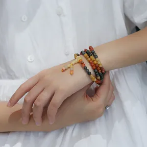 Macro detail of multi-layered Jinsiyu gemstone beads bracelet on a white dress