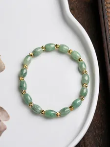 Primer plano de cuentas de jade verde natural con detalles dorados en plato cerámico