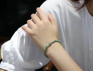 Close-up of light green jade beads bracelet with gold-tone spacers on a woman wrist