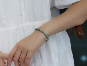 Detail of natural green jadeite rice beads bracelet with gold hollow spacers on wrist