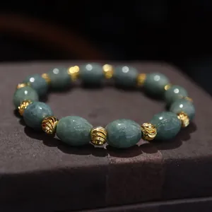 Macro shot of natural green jade beads and golden hollow spacer beads on a bracelet