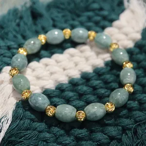 Detail of green jade beads with gold-textured spiral spacers on a knit background