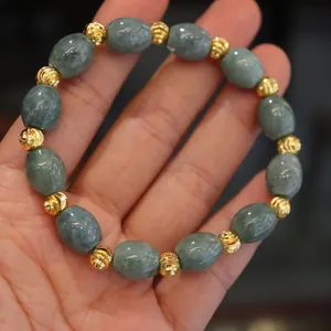 Macro shot of natural jadeite bead bracelet featuring gold-plated spacer beads on hand