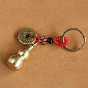 Macro shot of brass gourd pendant with ancient coins and red woven cord keychain