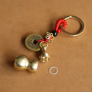 Detailed macro of a vintage brass hollow gourd keychain with red braided cord and coin