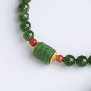 Macro detail of natural green jasper beads with carved cylinder bead and gold accents