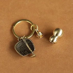 Macro detail of antique brass palm fan charm and screw-open gourd container keychain