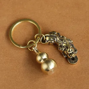Close-up of vintage brass keychain with detailed Pixiu and Wu Lou gourd charms