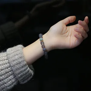 Dettaglio del bracciale di perle di agata viola con accento in giada verde al polso