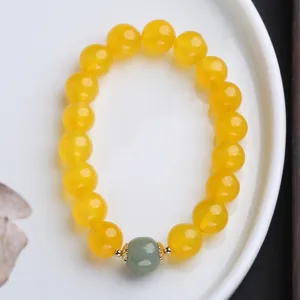 Dettaglio del bracciale in agata naturale con decorazioni floreali dorate su piatto