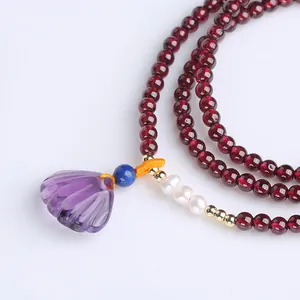 Detail of red garnet multi-strand bracelet with purple shell pendant and pearl accents