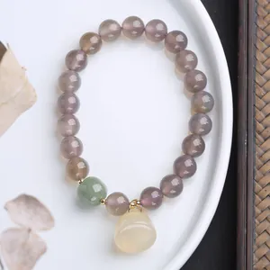 Détail du bracelet en agate grise avec pendentif lotus en jade et accents dorés