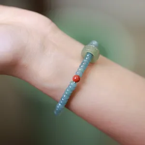 Macro view of blue-green jade abacus bead bracelet with red bead and lucky ring pendant
