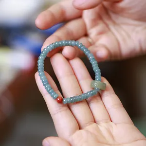 Close-up of faceted blue jade beads bracelet with red stone and carved jade tube