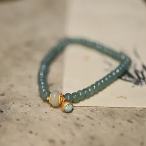 Macro view of jade abacus beads bracelet with gold accents and a blue pendant charm