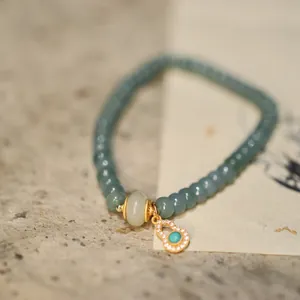Detailed close-up of blue jadeite beaded bracelet with a diamond-encrusted gourd pendant