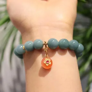 Blue agate bracelet with orange sphere charm and golden flower detail for women