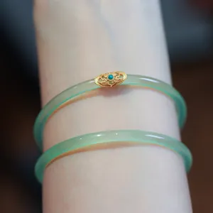 Detail of light green chalcedony bracelets with intricate golden filigree and turquoise bead