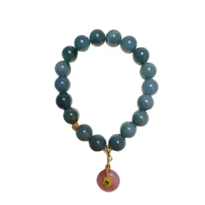 Blue jadeite and pink agate bead bracelet with a gold floral charm on white background