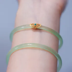 Detail of apple green agate bangles with golden filigree and blue gemstone in vintage style