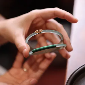 Macro detail of icy jade bangles with gold filigree and green zircon ruyi accents